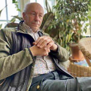 En äldre man sitter och ser fundersam ut. 