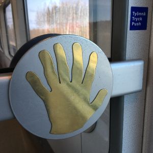 Kuudes sormi lisättiin ravintolavaunun messinkikäteen ilmeisesti pilke silmäkulmassa. kuusisorminen messinkikäsi ravintolavaunun ovessa