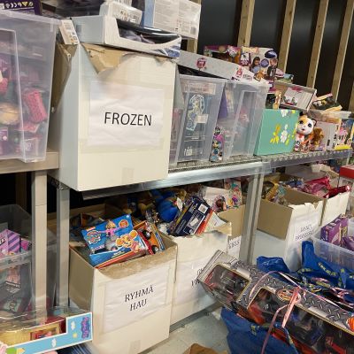 Leluja pahvilaatikoissa hyllyillä, parhaiten näkyvissä laatikoissa lukee Ryhmä Hau ja Frozen.
