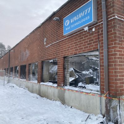 Tulipalossa tuhoutuneessa tehdasrakennuksessa ikkunat ovat särkyneet ja niiden kautta näkyy mustunutta tehtaan laitteistoa. 