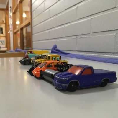 Små leksaksbilar står radade i en kö på ett bord.