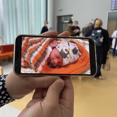 Hanna Wallenberg pitelee käsissään kännykkää josta näkyy kuva hänen pariviikkoisesta vauvastaan vastasyntyneiden teho-osastolla.