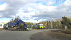 Tåget och specialtransporten körde vidare. Ett tåg och en transportbil med en grävmaskin på släp.