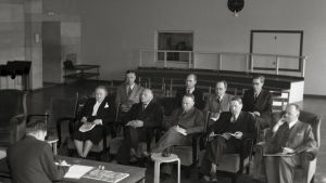 Rundradions bolagsstämma i radiohuset på Fabiansgatan 1946. Från vänster, framme: Hella Wuolijoki, okänd, tekniska direktören Juho Rissanen, okänd, Yle-profilen Markus Rautio. Från höger, bakre raden: Vennola, Jussi Koski Luoma. Oy Yleisradio Ab:n varsinainen yhtiökokous Fabianinkadun radiotalossa. Vasemmalta lukien Hella Wuolijoki, tuntematon mieshenkilö, tekninen johtaja Juho Rissanen, tuntematon mieshenkilö ja Markus Rautio. Takarivissä oikealta lukien ensimmäisenä mahdollises