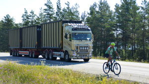 På riksväg 25 delar du väg med väldigt stora, tunga fordon. En cyklist cyklar på en riksväg. Bakom cyklisten kör en stor långtradare.