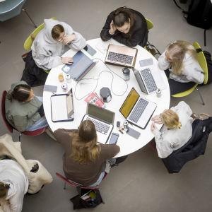 Opiskelijoita pyöreiden pöytien ääressä ylhäältä kuvattuna.