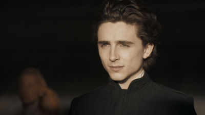 Närbild på Timohée Chalamet i svart, prästliknande slängkappa.