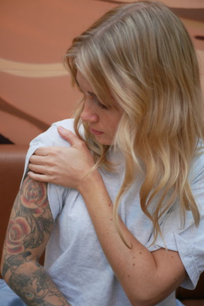 Flicka drar upp ärmen på sin tröja för att visa sin tatuering