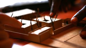 Hollmén Reuter Sandman architects miniatyrmodell av barnhemmet TunaHaki i Tanzania. Fingrar pekar på miniatyrmodell av barnhemmet TunaHaki i Tanzania.