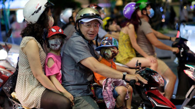 Perhe matkustaa skootterilla Vietnamin suurimmassa kaupungissa Ho Chi Minh Cityssa.