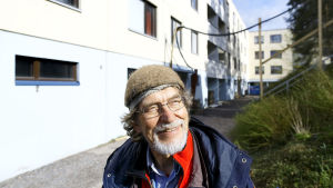 Mauri Tahvanainen hymyilee taloyhtiön pihalla.