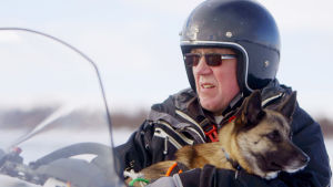 Tage Fjälborg på sin skoter med hunden Kompis i famnen. Tage Fjälborg på sin skoter med hunden Kompis i famnen.