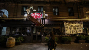En restaurang i centrala Neapel protesterar mot den italienska regeringens nya regler som tvingar restaurangerna att stänga klockan 18. Krögarna har hängt två dockor och en likkista utanför restaurangen. En banderoll utanför restaurangen lyder: "Vi hoppas på stöd från regeringen för att det inte ska sluta så här." En restaurang i Neapel protesterar mot den italienska regeringens restriktioner med att hänga två dockor och en likkista utanför restaurangen. En banderoll utanför restaurangen lyder: "Vi hoppas att regeringen hjälper oss så att det inte ska så här illa"