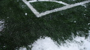 Man kan spela ligafotboll på en konstgräsplan utan problem då det fortfarande finns snö på marken. Vit gränslinje på grönt konstgräs samt snö.