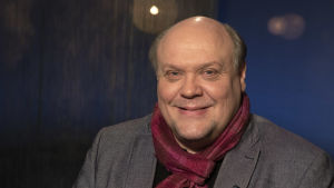Näyttelijä Hannu-Pekka Björkman Mediapoliksen studiolla Tampereella Ani Kellomäen vieraana. H-P katsoo kameraan ja hymyilee tyylikäs punainen huivi kaulassaan.