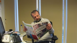 Henrik Othman läser Österbottens tidning i det nya tabloidformatet 2014. En man sitter vid ett skrivbord och läser Österbottens tidning.