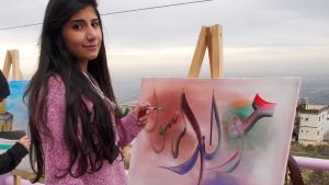 Nuori nainen seisoo maalauksen edessä sivellin kädessä.
