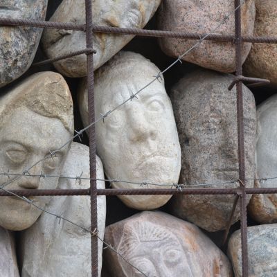 Ansikten av sten bakom taggtrådsgaller, ett minnesmärke över offren för kommunisttidens förtryck