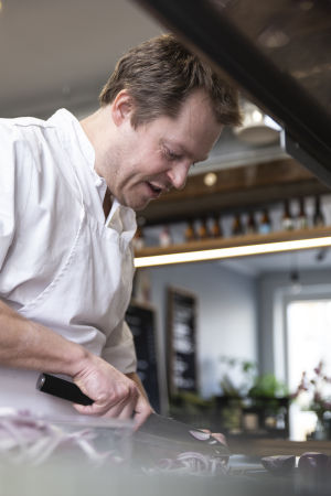 Skivandet av till exempel grönsaker tar sin egen tid innan restaurangen öppnar. Nick Victorzon skär rödlök med kniv.
