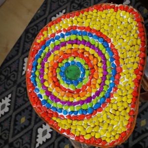 Mosaikstenar i olika färger limmade på en stubbe.