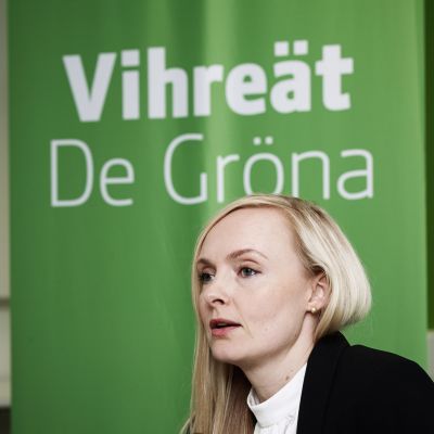 Maria Ohisalo i förgrunden, i bakgrunden en affisch med texten Vihreät De Gröna.