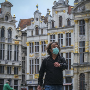 Munskydd har blivit en vanlig syn i Belgiens huvudstad Bryssel. En man med munskydd går över Bryssels historiska torg grand place