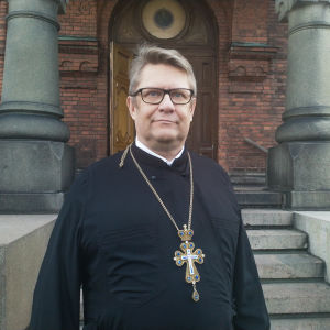 - Vi vill göra det lättare för folk att komma till kyrkan, inte svårare, säger Markku Salminen, kyrkoherde för Helsingfors ortodoxa församling. Markku Salminen, kyrkoherde vid Helsingfors ortodoxa församling, står framför en trappa in till Uspenskijkatedralen på Skatudden i Helsingfors. Han ser allvarsam ut och blickar ut bakom kameran.