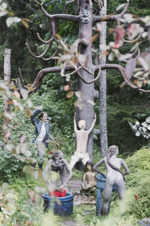Pesijättäret – ja taustalla kohtaus, jossa patsasta piiskataan. Patsaita jotka esittävät naisia pyykkäämässä vaatteita sinisissä paljuissa.