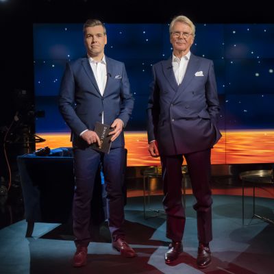 Daniel Olin och Björn Wahlroos står i tevestudion bägge iklädda blå kostym och vit skjorta utan slips