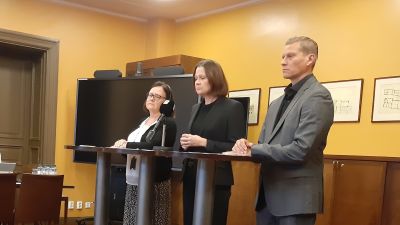 Riitta Liuksa, Minna Arve och Tuomas Heikkinen, tre tjänstemän i Åbo, står allvarliga bakom tre höga bord på en presskonferens.