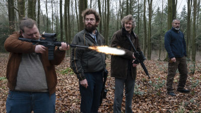 Otto (Nikolaj Lie Kaas), Markus (Mads Mikkelsen), Emmenthaler (Nicolas Bro) och Lennart (Lars Brygmann) står ute i skogen och ser på då Emmenthaler skjuter med automatvapen. sitter i en bil och ser allvarliga ut.