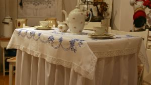 Prydlig servis och dolda ben på museum i Rybnik i Polen. Närbild på ett bord dukat med kaffeservis och en bordsduk som sträcker sig ända ner till golvet.