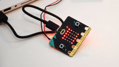 En liten microbitskiva med röda lysdioder på ett bord.