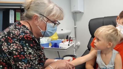 Pojke tittar på en vårdare som precis ska ge honom vaccin.