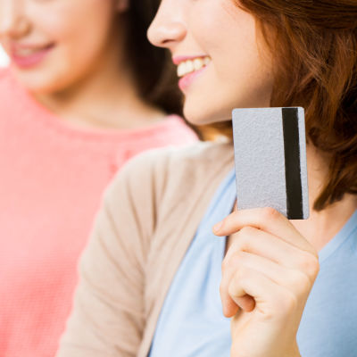 leende kvinna håller upp kreditkort