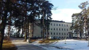 Esperi Hoitokoti Rehabia i Bjärnå. En snöig väg och snöig fotbollsplan framför en ljusgul byggnad i fyra våningar, Esperi Hoitokoti Rehabia.