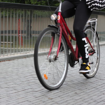 En röd cyklist cyklar över biblioteksbron i Åbo. 