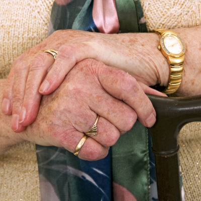 En äldre persons händer på en käpp.