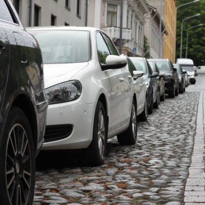 En rad av parkerade bilar längs en gata.
