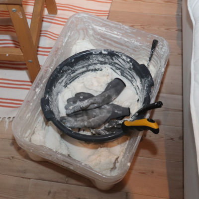 Vitt pulver, som är amfetamin, i en plastlåda på ett trägolv.