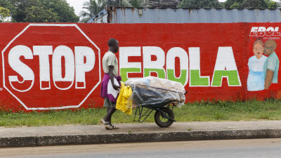 En man går förbi en vägg med texten "Stop Ebola" i Liberias huvudstad Monrovia den 6 oktober 2014.