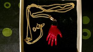 Halssmycke som såldes på Conversations with Nick Cave-turnén Röd hand-smycke. Har att göra med Nick Caves Red Right Hand