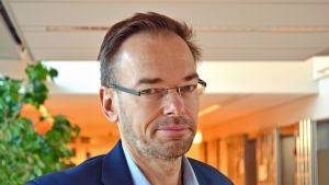 Folktingssekreterare Markus Österlund godkänner regeringens nya förslag. Markus Österlund poserar i en korridor.