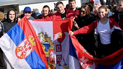 Anhängare till tennisspelaren Novak Djokovic som håller upp flera serbiska flaggor.