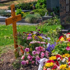 Massvis av blommor på en nygrävd grav på en kyrkogård.
