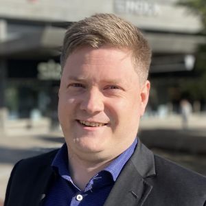 Mansantagen person poserar på torg.
