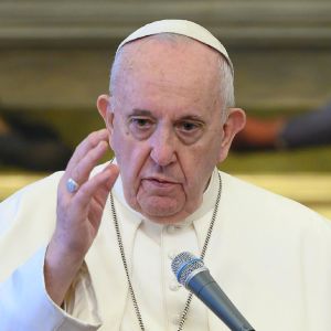 En äldre man i vit dräkt och vit huvudbonad samt ett stort metallkors på bröstet. Påven Franciskus i Vatikanen den 17 juni 2020.