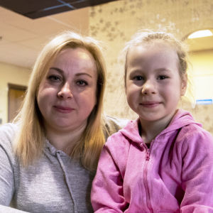 Olga Narozhnaya och hennes dotter Alina sitter vid ett bord på en mottagningscentral. 