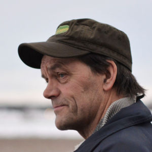 Man i keps blickar ut mot en åker.