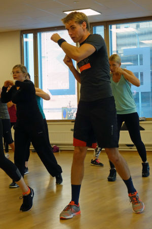 Mikael Lindgren håller på med det högintensiva gruppträningsprogrammet bodycombat, där man utför rörelser från flera kampsporter. Mikael Lindgren tränar bodycombat i grupp i en konditionssal i Esbo.